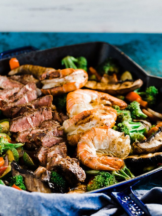 A Surf n' Turf Paleo bowl with Steak and Shrimp, over bell peppers, shallots, portabella mushroom, zucchini with a savory seasoning.