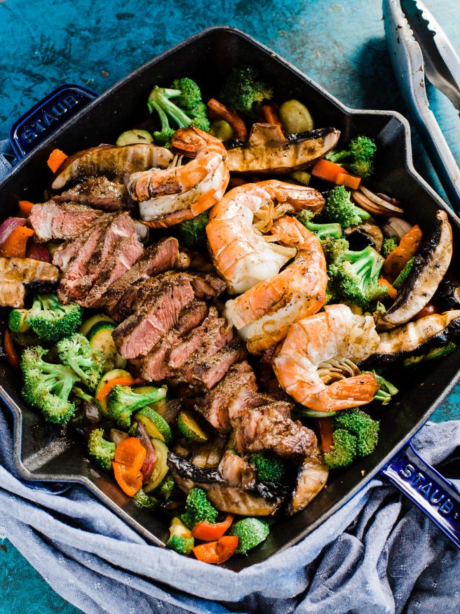 A Surf n' Turf Paleo bowl with Steak and Shrimp, over bell peppers, shallots, portabella mushroom, zucchini with a savory seasoning.