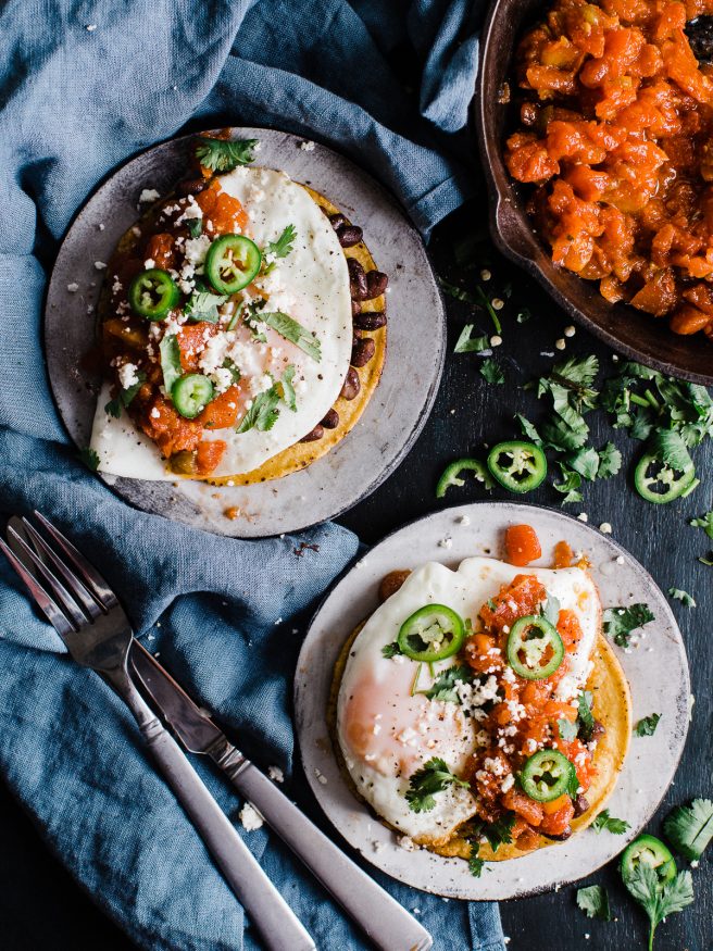 Huevos Rancheros Tostadas makes a great breakfast for dinner, or bunch meal. Topped with black beans, a from scratch salsa, then topped with a fried egg cojita cheese and serrano peppers