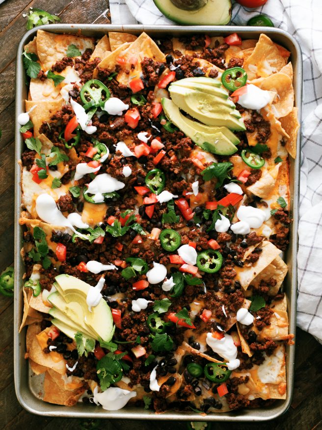 Taco Night Sheet Pan Nachos are a great way to put a spin on taco night. Taco seasoned ground beef and all your favorite taco toppings on sheet pan nachos.