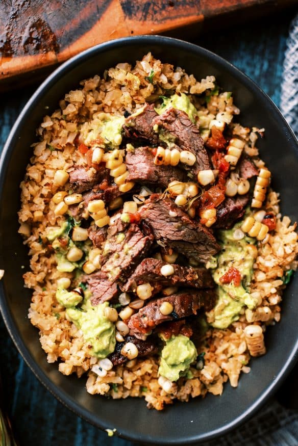 Cilantro Lime Cauliflower rice topped with fresh guacamole, and perfectly seasoned flank steak for a great low carb lunch or dinner!